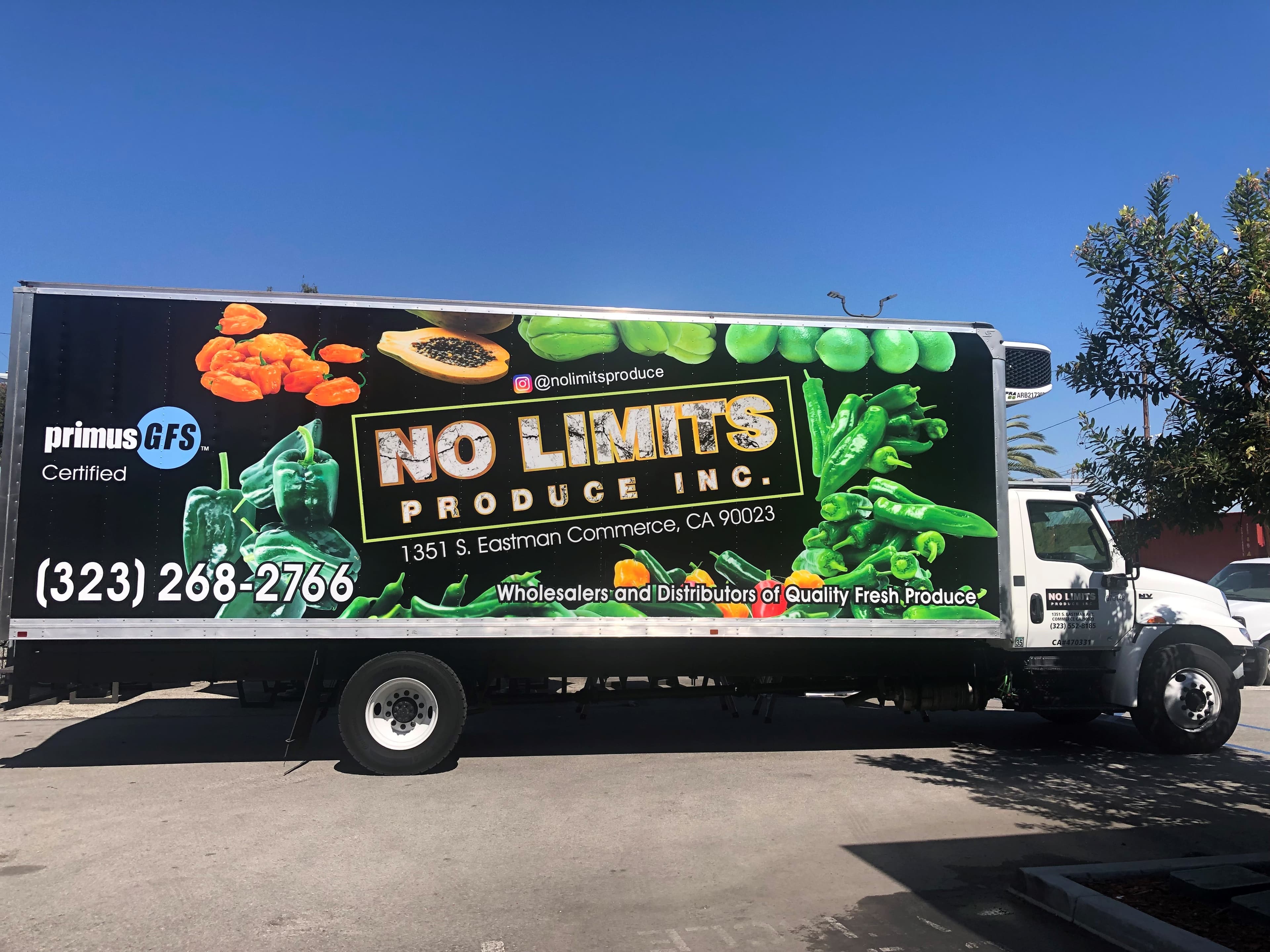 Black box truck wrapped with photographic peppers and produce, large yellow No Limits Produce lettering and a phone number
