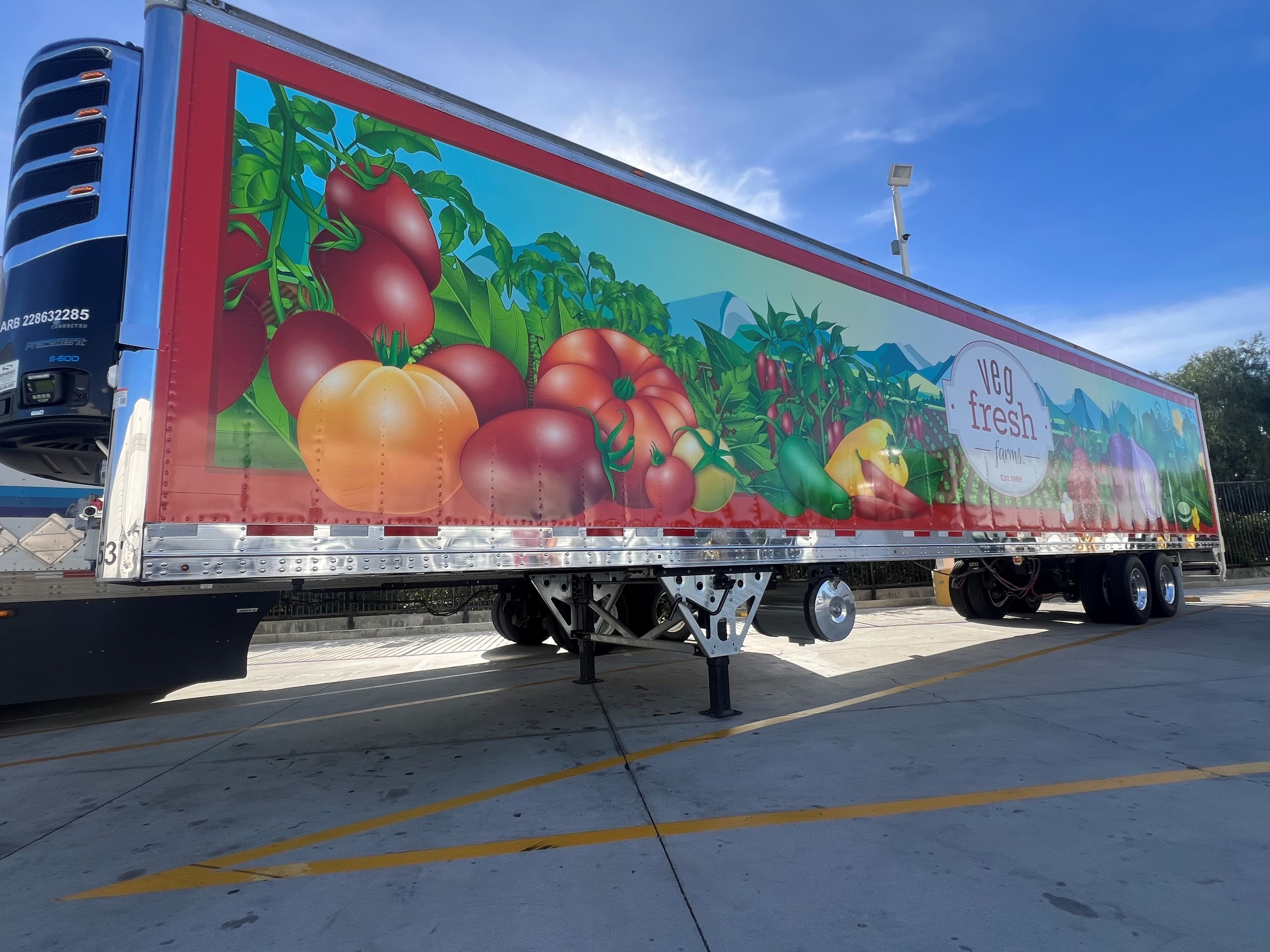 Refrigerated trailer wrapped with a full-length illustration of tomatoes, peppers and vegetables against a mountain landscape