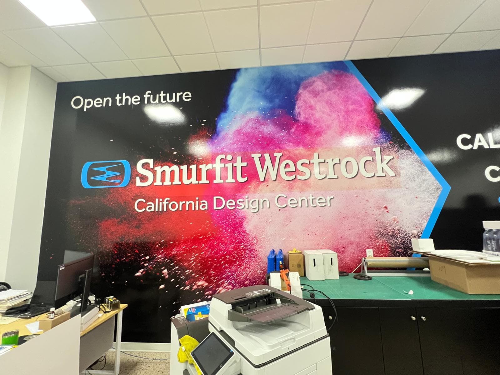 Full-wall interior graphic with a colour powder burst, reading Open the future, Smurfit Westrock California Design Center