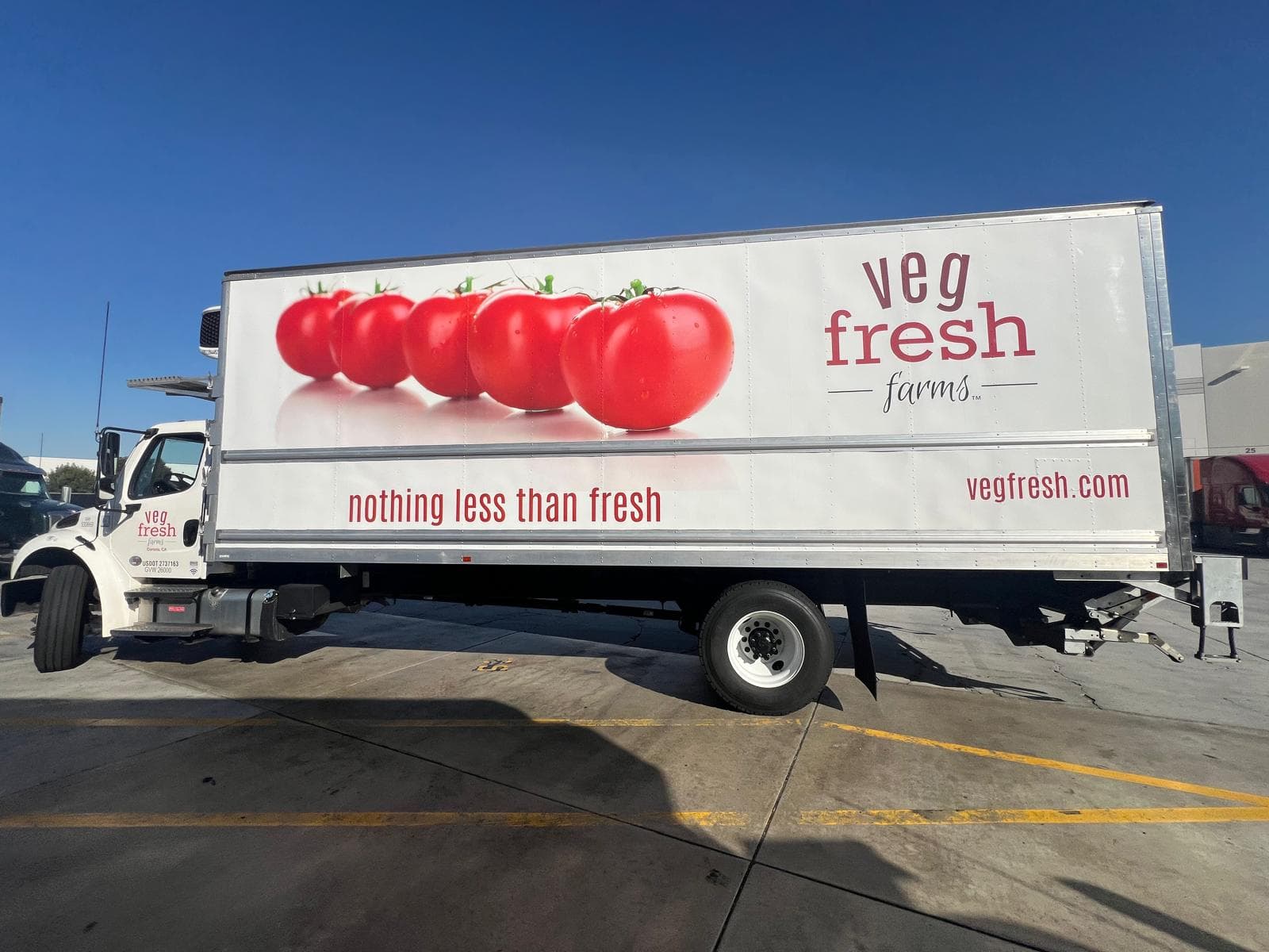White box truck with a photographic tomato graphic and the Veg Fresh Farms wordmark along the cargo body
