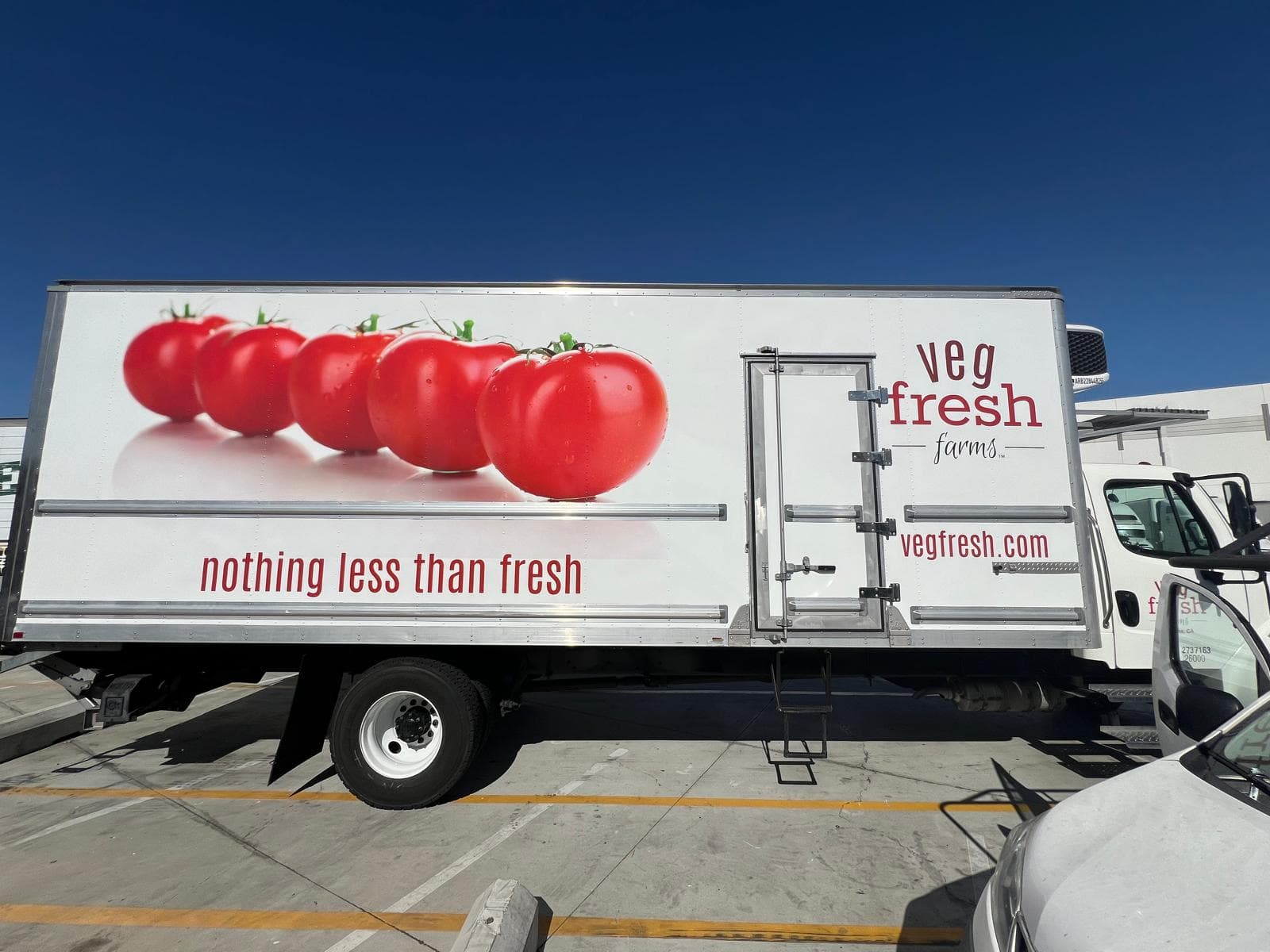 Side view of a second Veg Fresh Farms box truck carrying matching produce graphics