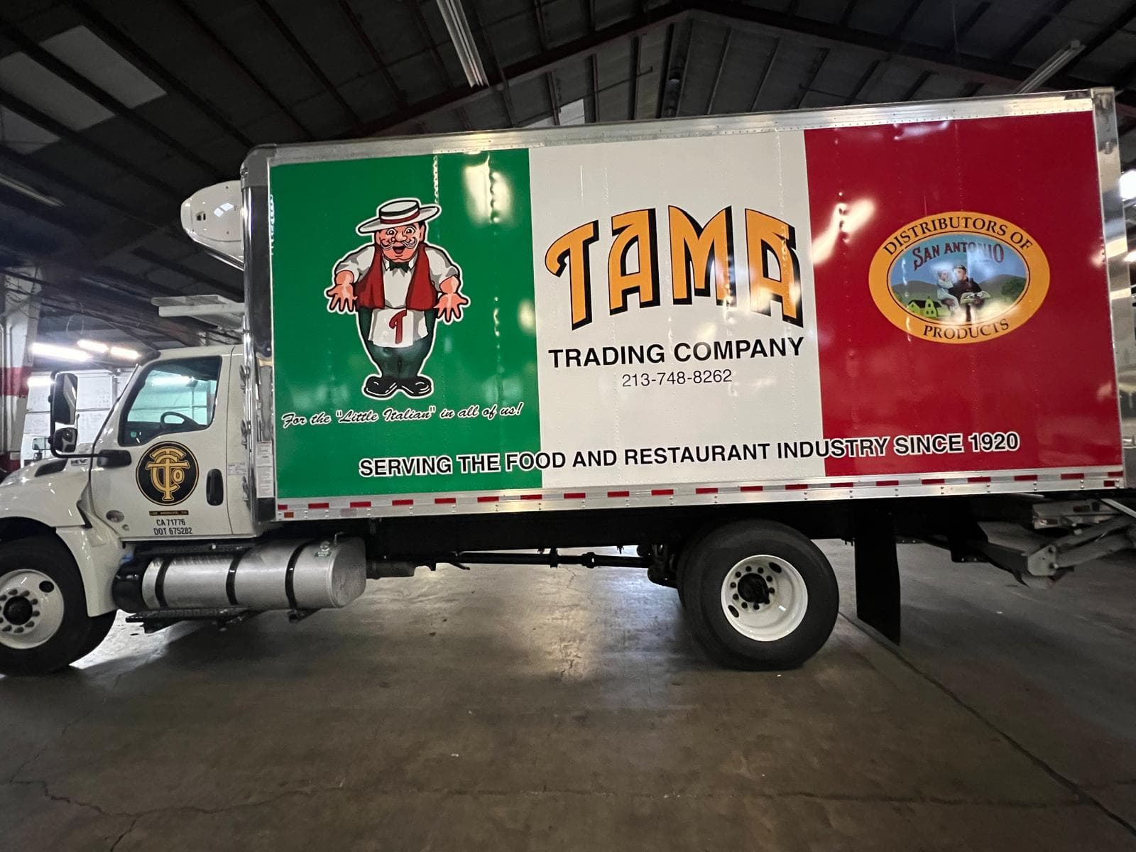 White box truck with green, white and red panel graphics, an illustrated chef character and Tama Trading Company lettering