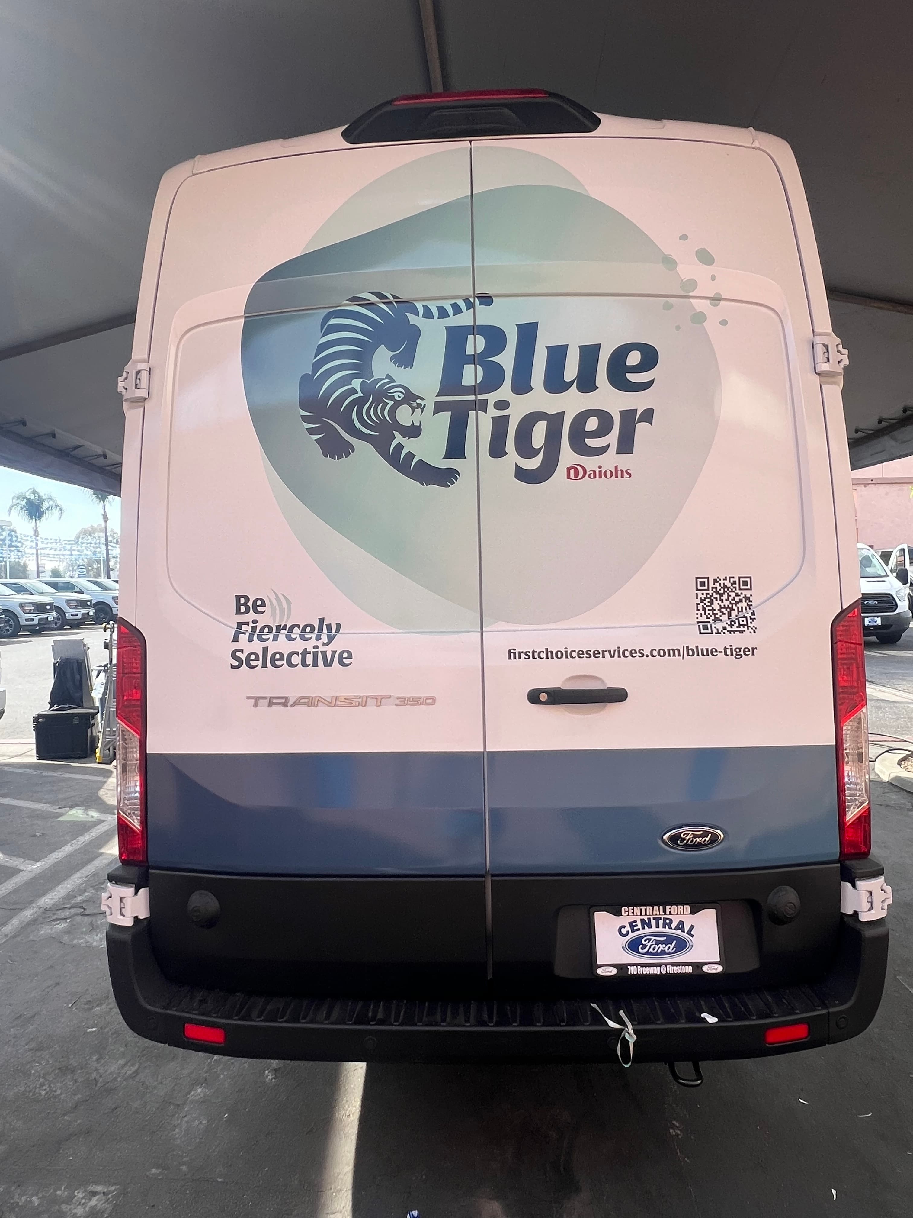 Rear doors of a white Ford Transit van carrying a Blue Tiger logo, tagline and QR code